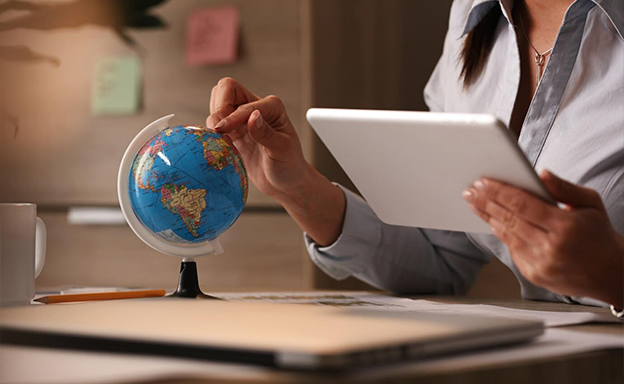 Person pointing at globe while using tablet with immigration consultants in kerala